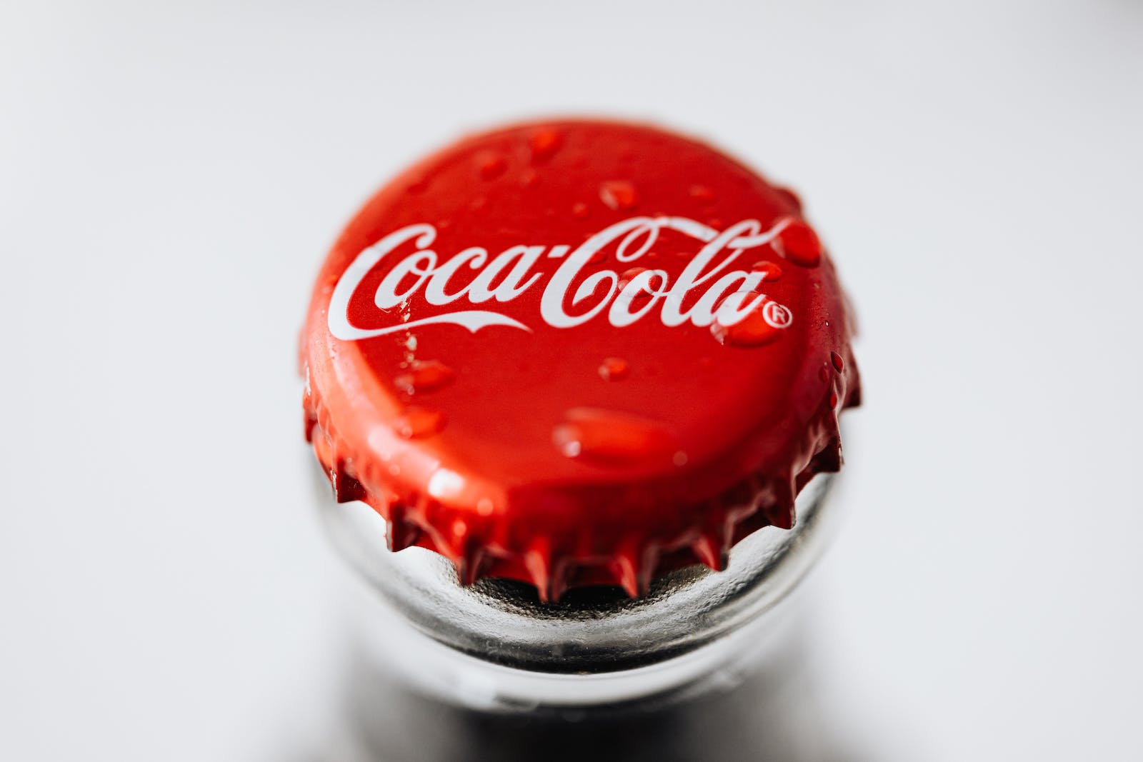 Nahaufnahme eines roten Kronkorkens mit der ikonischen Wortmarke von Coca-Cola